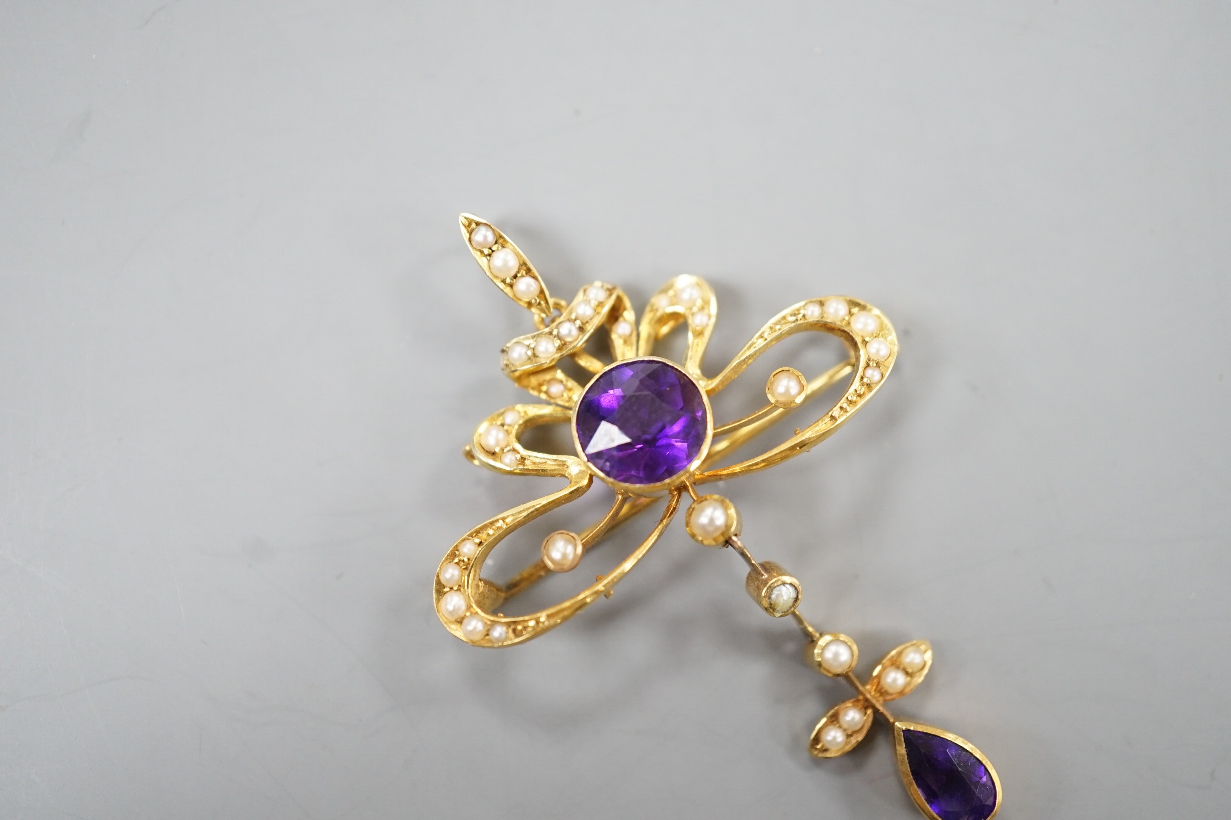 An Edwardian 15ct, amethyst and seed pearl set drop pendant brooch, overall 49mm, gross weight 5.3 grams.